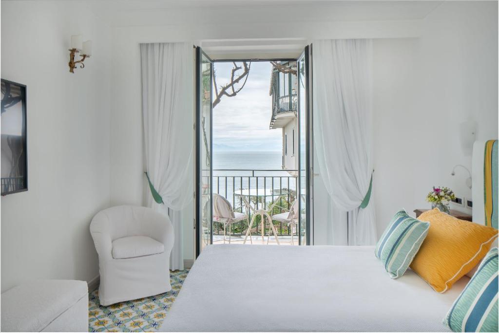 a bedroom with a bed and a chair and a balcony at Hotel Santa Caterina in Amalfi
