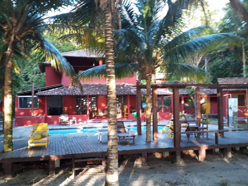 um resort com piscina e palmeiras em Pousada ZEN em Cumuruxatiba