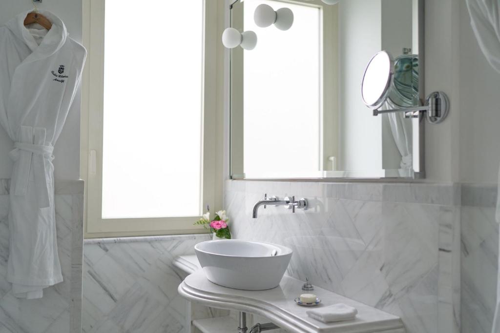 a white bathroom with a sink and a mirror at Hotel Santa Caterina in Amalfi