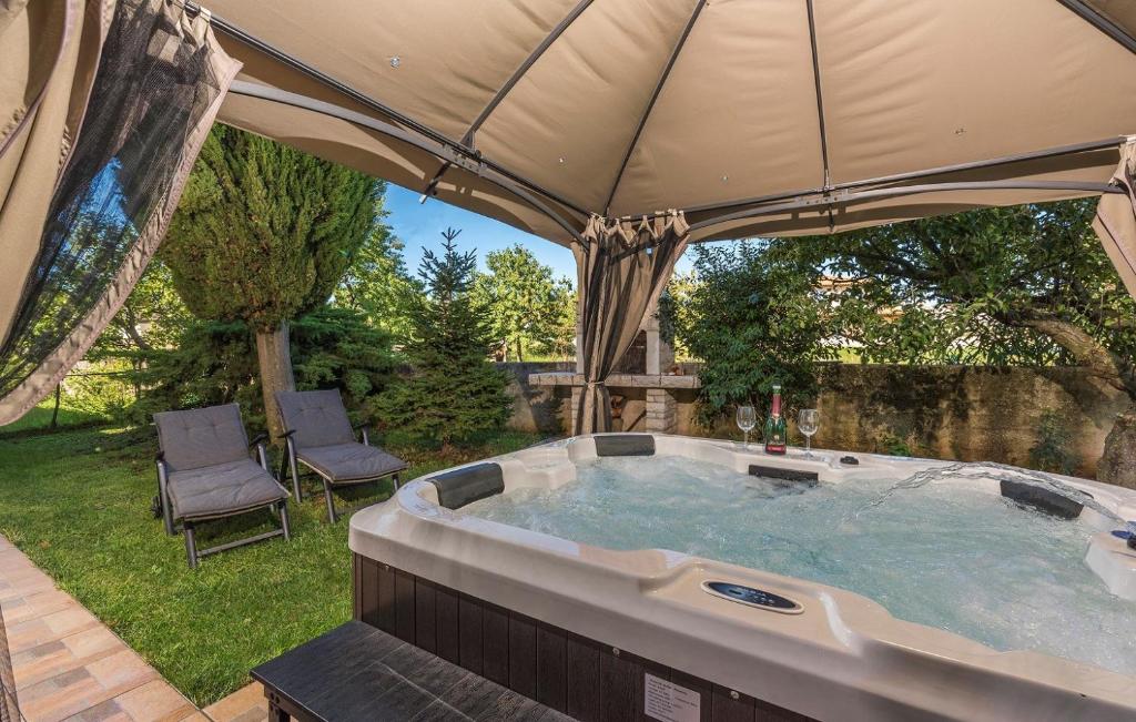 a hot tub under an umbrella in a yard at Apartment Maružini in Kanfanar