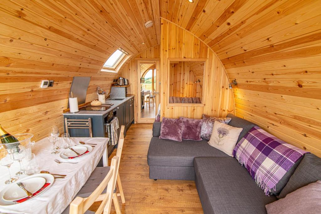a living room with a couch and a stove in a cabin at Schiehallion Luxury Glamping Pod with Hot Tub at Pitilie Pods in Aberfeldy