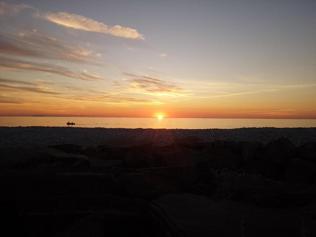 um pôr do sol na praia com um barco na água em bilocale Marina di Pisa em Marina di Pisa