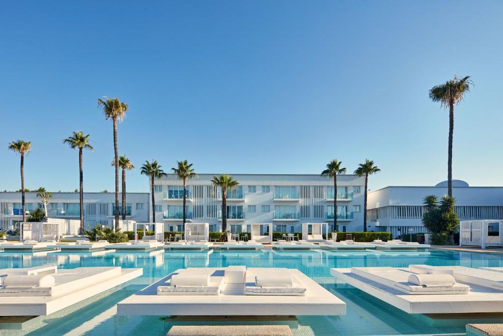 a large swimming pool with a row of tables and chairs at So White Club Resort in Ayia Napa
