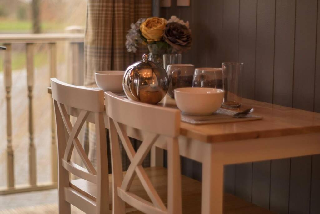 a wooden table with chairs and a vase with flowers at The Treehouse - Sleeps 4 in Old Leake