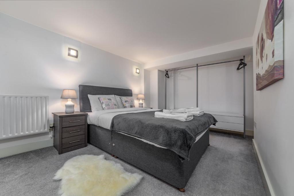 a bedroom with a large bed with a nightstand and a window at Suites by Rehoboth - Building XXII - Royal Arsenal in Woolwich