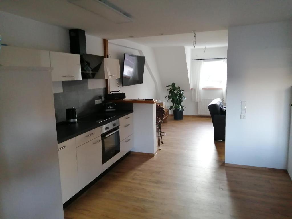 a kitchen with white cabinets and a wooden floor at Ferienwohnung Maja in Waldkirch