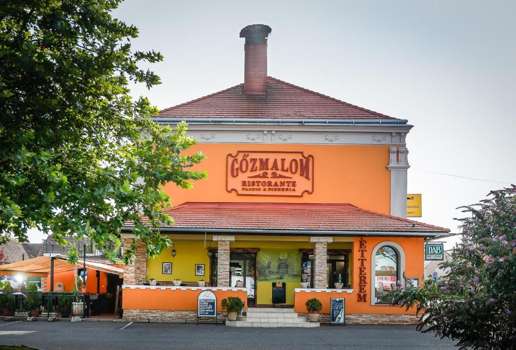 ein orangefarbenes Gebäude mit einem Schild darüber in der Unterkunft Gőzmalom Étterem és Panzió in Körmend