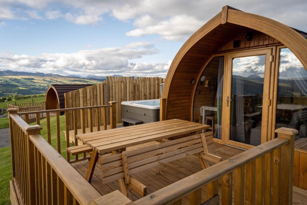 a wooden deck with a wooden bench and a table at Farragon Luxury Glamping Pod with Hot Tub & Pet Friendly at Pitilie Pods in Aberfeldy