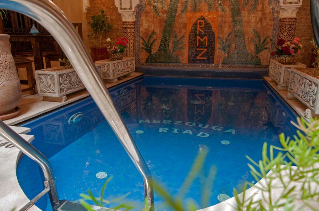 a swimming pool in a house with a tile wall at Riad Merzouga in Marrakech