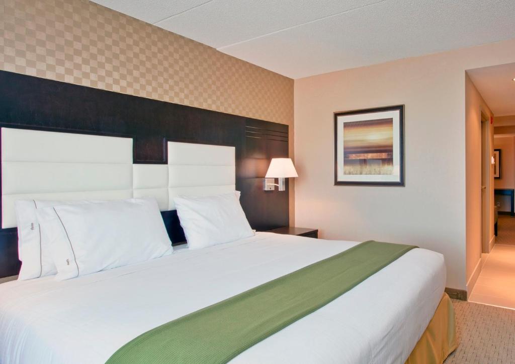 a hotel room with a large bed with white pillows at Holiday Inn Express & Suites Ottawa West - Nepean by IHG in Ottawa