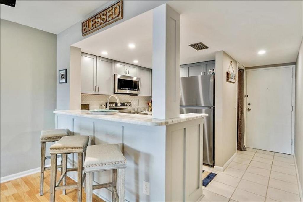 Una cocina con una encimera con taburetes y un refrigerador. en Unit 3206 - Ocean & Racquet Resort, en St. Augustine Beach