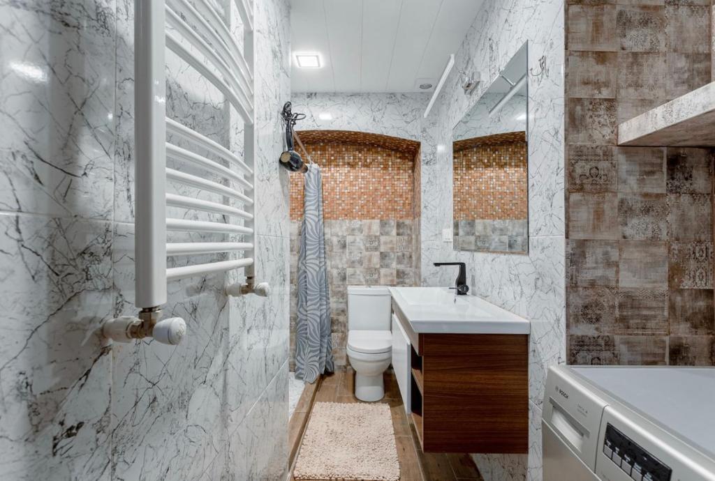 Baño blanco con aseo y lavamanos en lovely Dulcet Loft In Center Of Rustaveli, en Tiflis