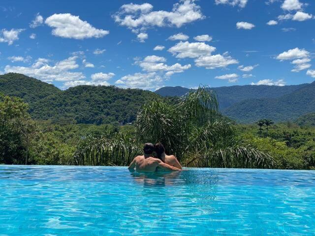 um homem e uma mulher numa piscina na água em Vista Mágica na Praia de Camburizinho A em São Sebastião