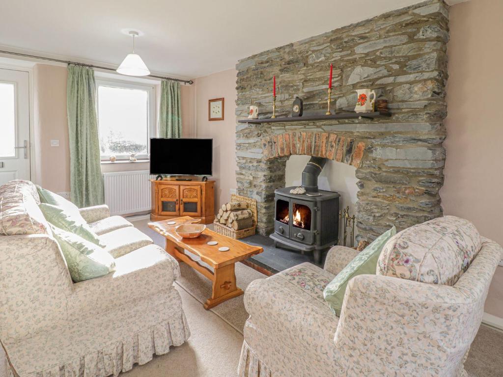 a living room with a stone fireplace with two couches at 1 Rhys Terrace in Pennal