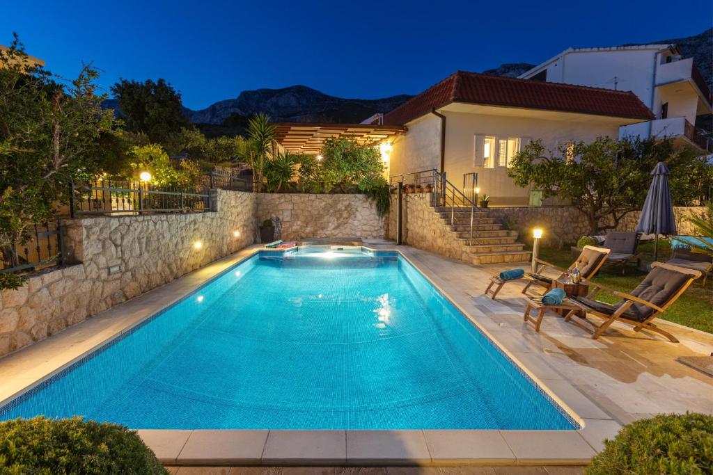 una piscina en un patio trasero con una casa en Villa OLD OLIVE, 3lovelyvillas, en Podgora