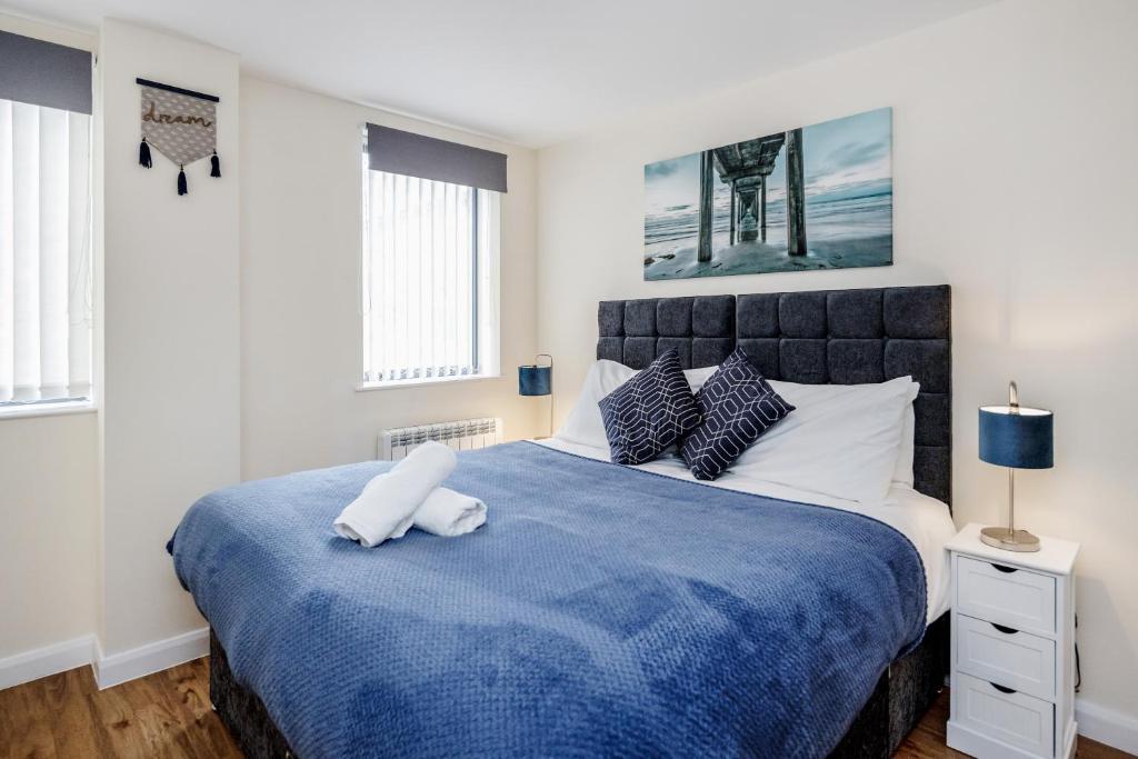 sypialnia z dużym łóżkiem i niebieskim kocem w obiekcie Queens Serviced Apartments - F1 w mieście Watford