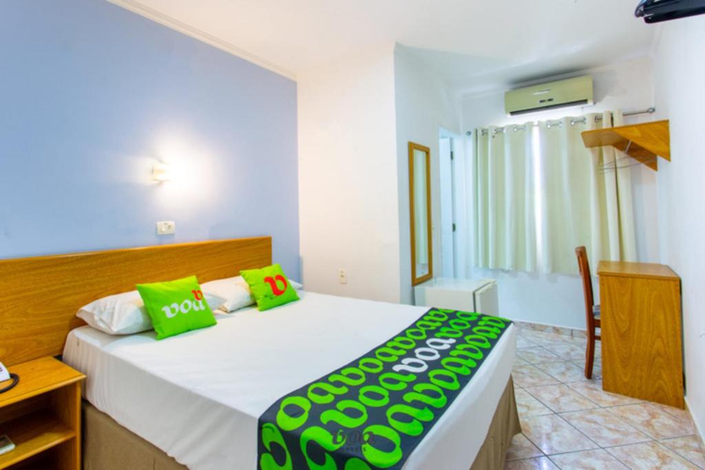 1 dormitorio con 1 cama grande con almohadas verdes en VOA Convenience Hotel, en Jundiaí