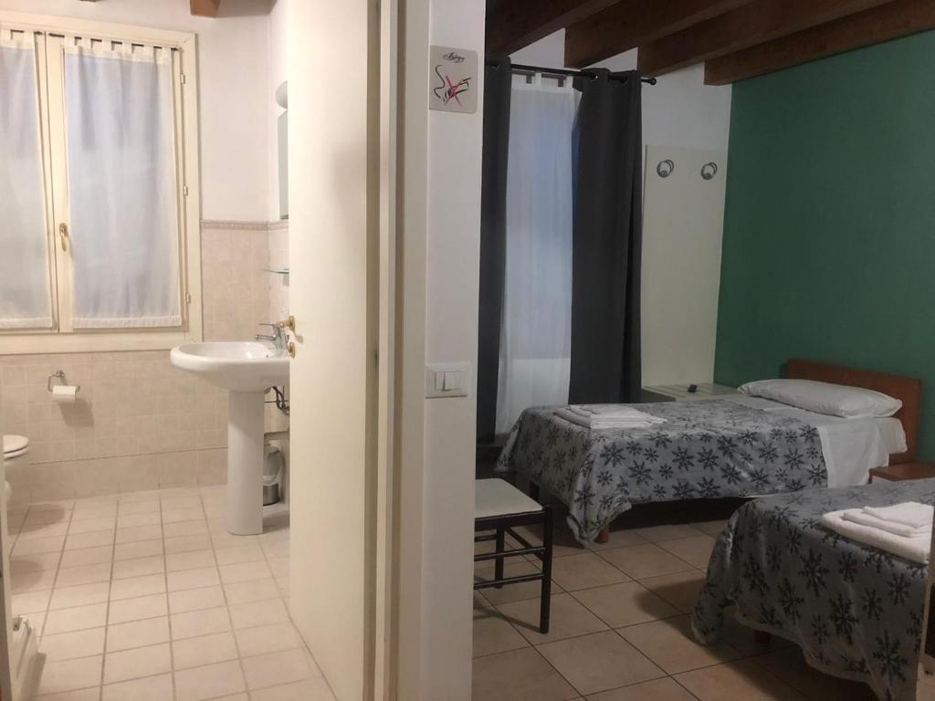 une chambre avec deux lits et une salle de bain avec lavabo dans l'établissement IL Borgo, à Modène