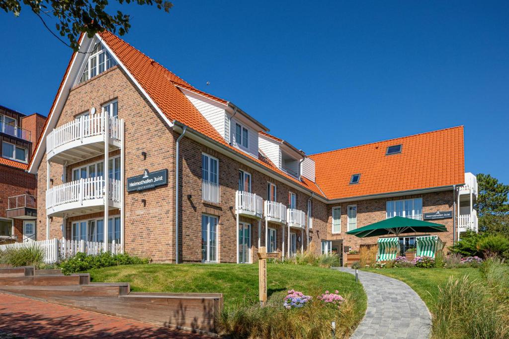 un grand bâtiment en briques avec un toit orange dans l'établissement Heimathafen Juist, à Juist