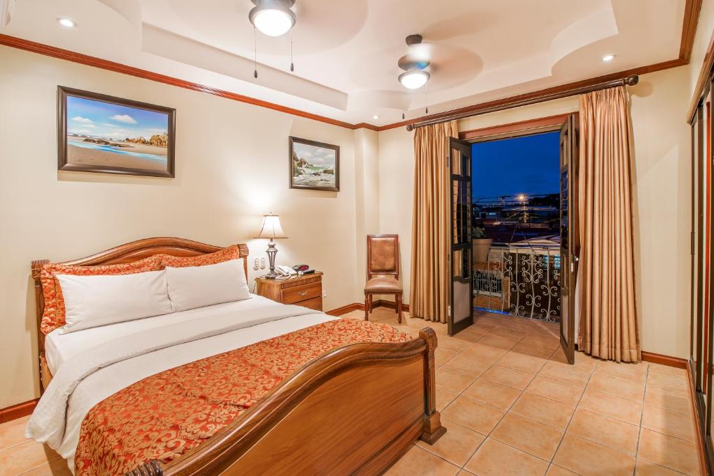 a bedroom with a bed and a large window at Hotel Casa Roland San Jose in San José