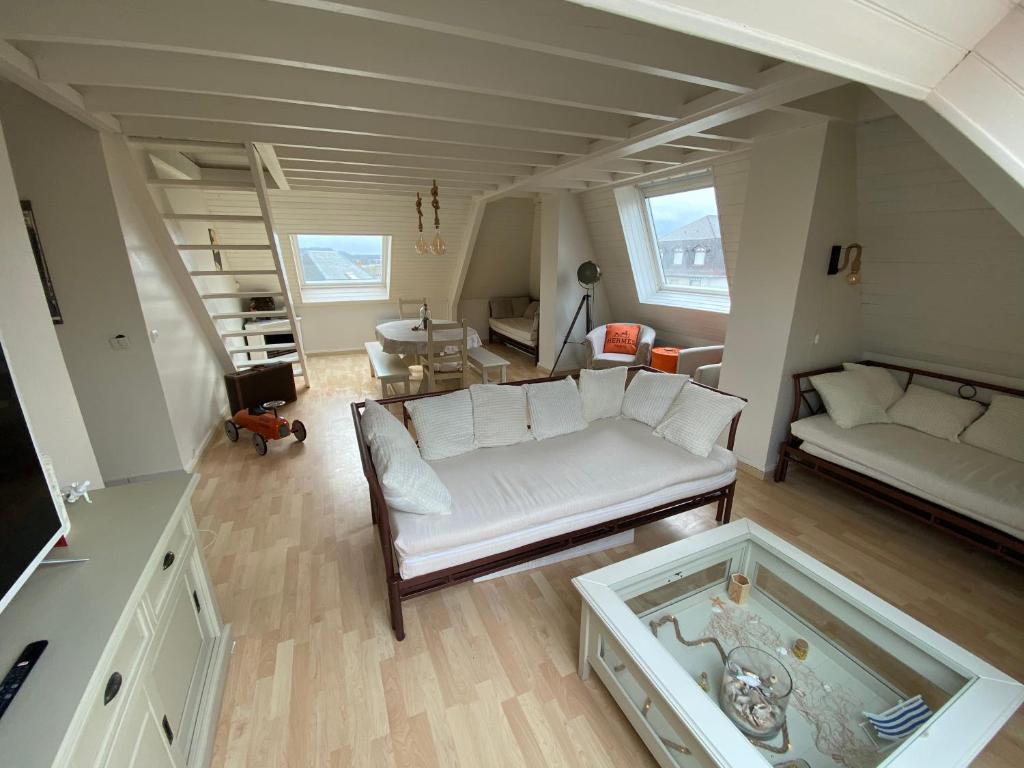 ein Wohnzimmer mit einem weißen Sofa und einem Tisch in der Unterkunft Appartement Vue Mer - Cabourg - Normandie in Cabourg