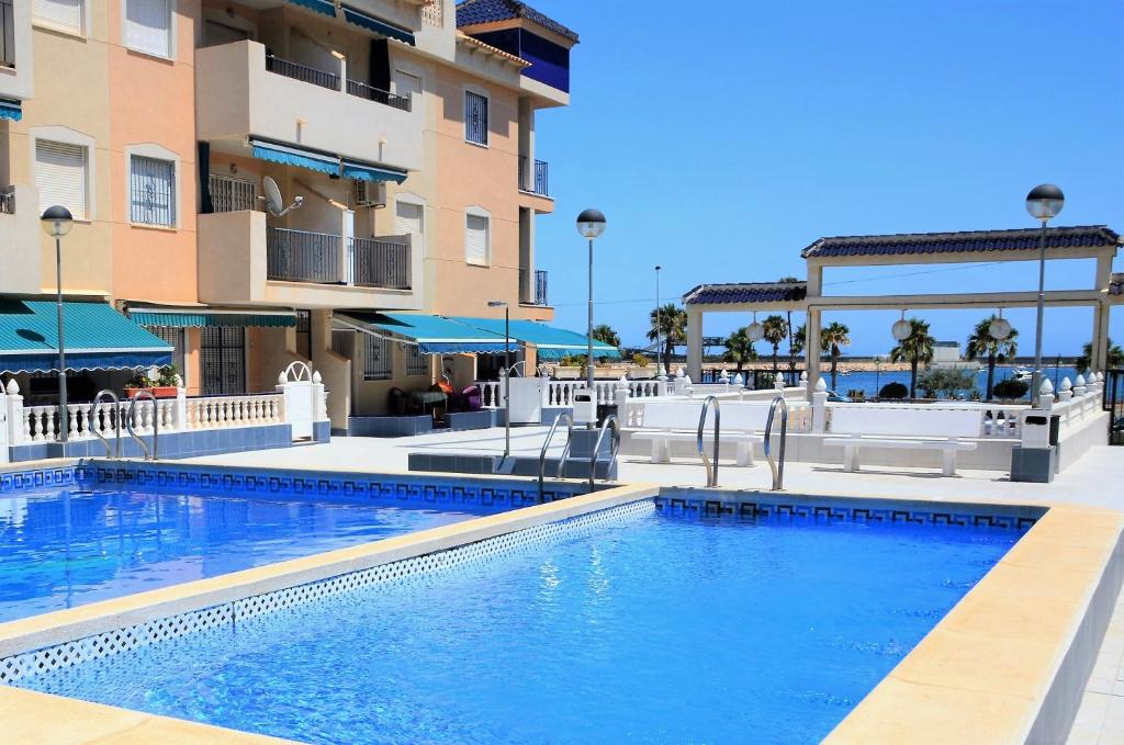 a swimming pool in front of a building at Naufragos Beach Apartment in Torrevieja