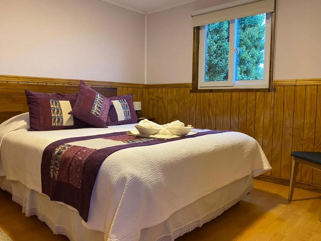 1 dormitorio con 1 cama grande y ventana en Hostal America en Puerto Natales en Puerto Natales