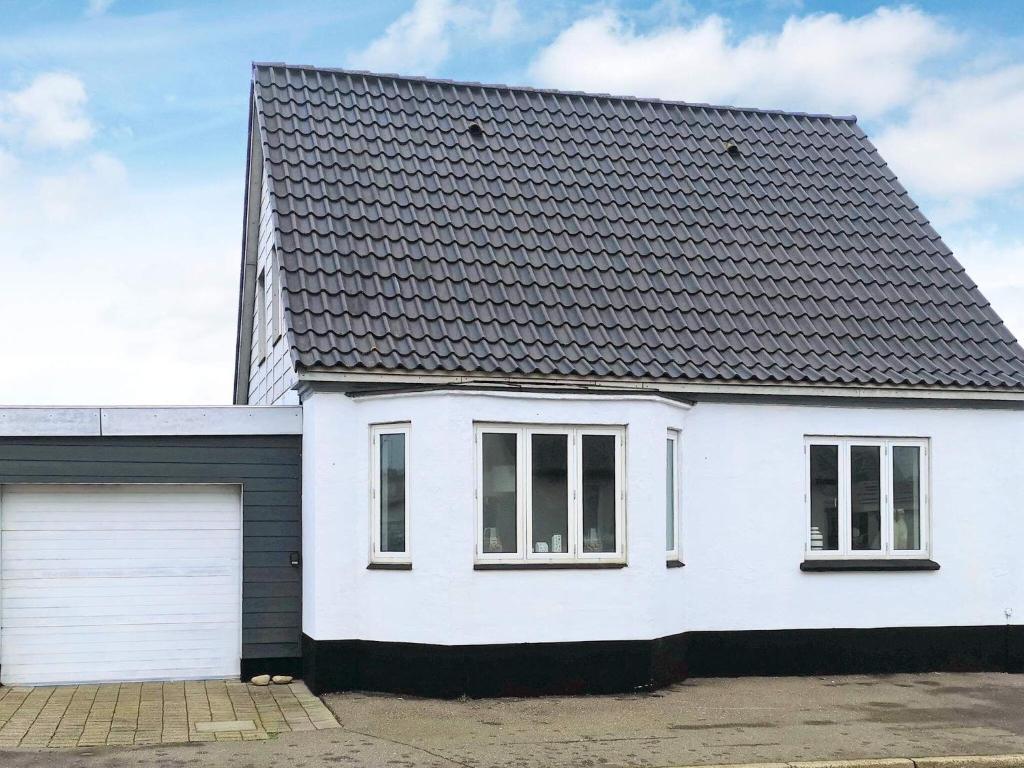 una casa blanca con techo negro y garaje en Holiday home Thyborøn IV, en Thyborøn