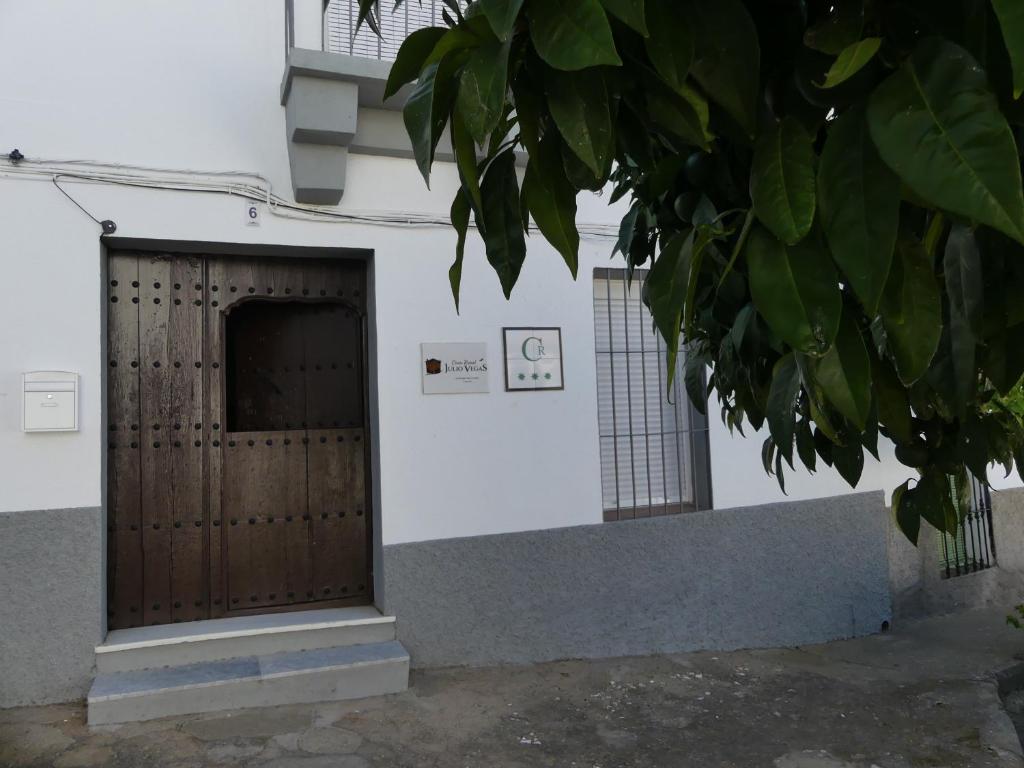 un edificio con una puerta de madera y un árbol en Casa Rural Julio Vegas, en Santiago del Campo