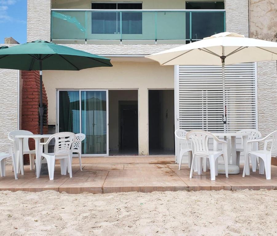 una mesa y sillas con sombrillas frente a una casa en Casa em Maragogi, en Maragogi