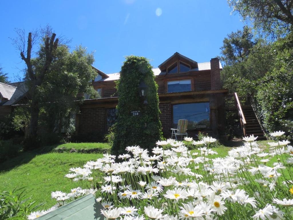 un jardin avec des fleurs blanches en face d'une maison dans l'établissement Cabaña Paseo del Sol, à San Martín de los Andes