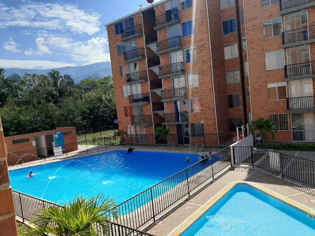 a large swimming pool in front of a building at Apartamento Vacacional Toscana Melgar in Melgar