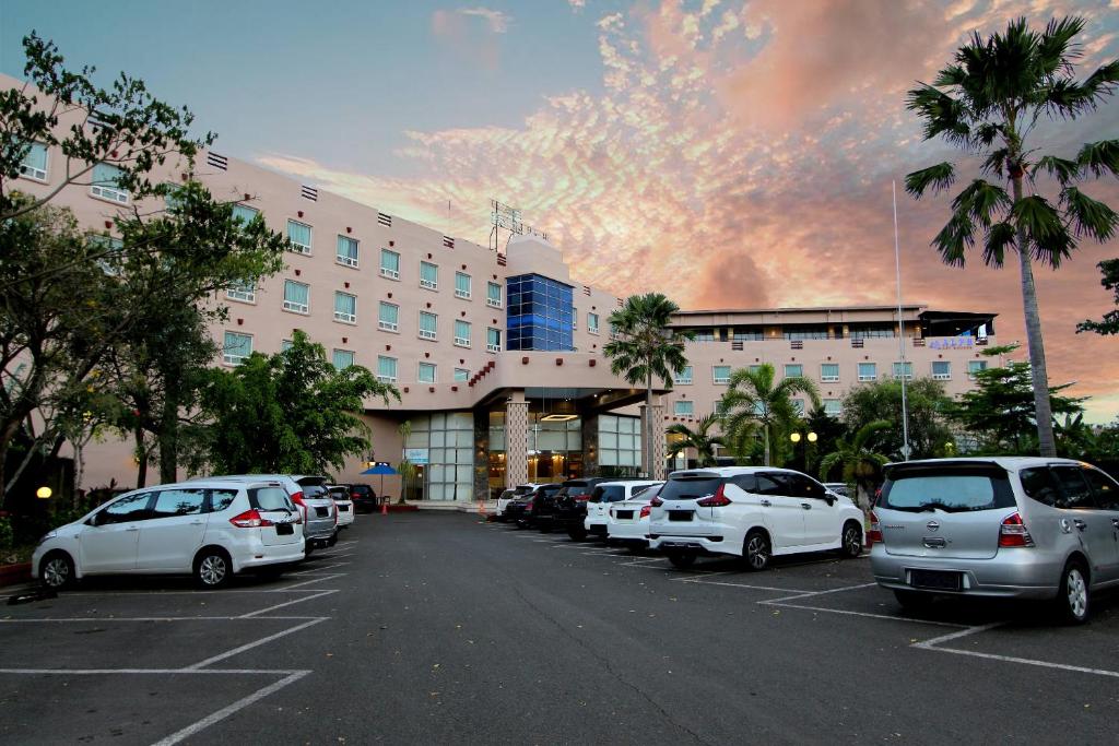 un parking avec des voitures garées devant un bâtiment dans l'établissement Forbis Hotel, à Serang