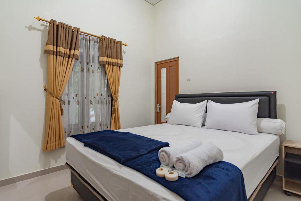 1 dormitorio con 1 cama con toallas en The Lima Guest House Syariah Mitra RedDoorz, en Cirebon