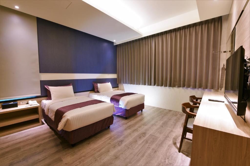 Yu Kun Tien Hotel في Shalu: غرفة فندقية بسريرين وتلفزيون بشاشة مسطحة