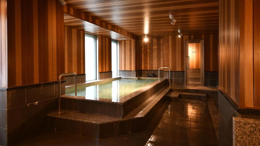 een zwembad met water in een kamer met houten wanden bij Bell's Inn Tsuchiura in Tsuchiura