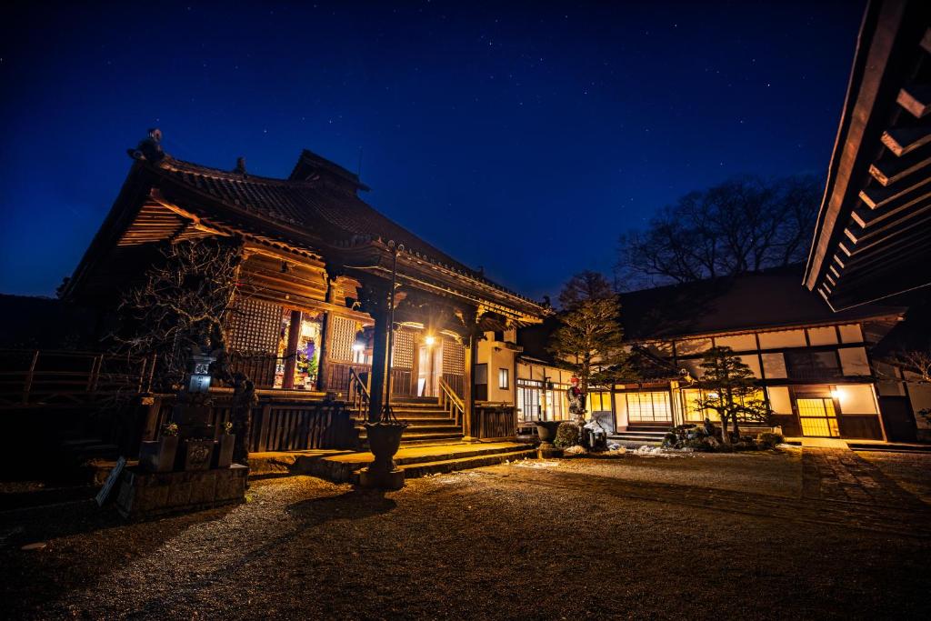 a wooden building with lights on it at night at Temple Hotel 正暦寺 in Ayabe