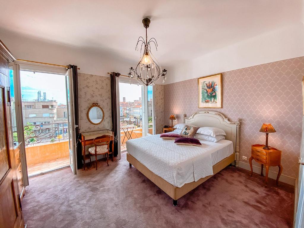 a bedroom with a bed and a large window at Hotel Relais Du Postillon in Antibes