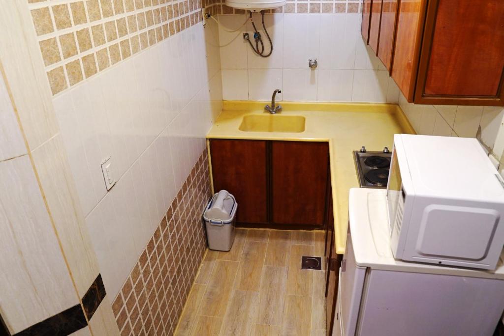 a small kitchen with a sink and a trash can at Loaloat Al Bahar in Al Khobar