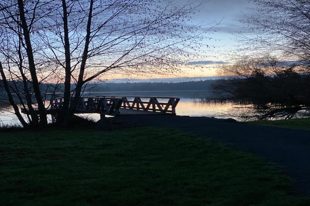 um banco sentado ao lado de um lago ao pôr-do-sol em Meadowbrook Guest Suite em Brentwood Bay