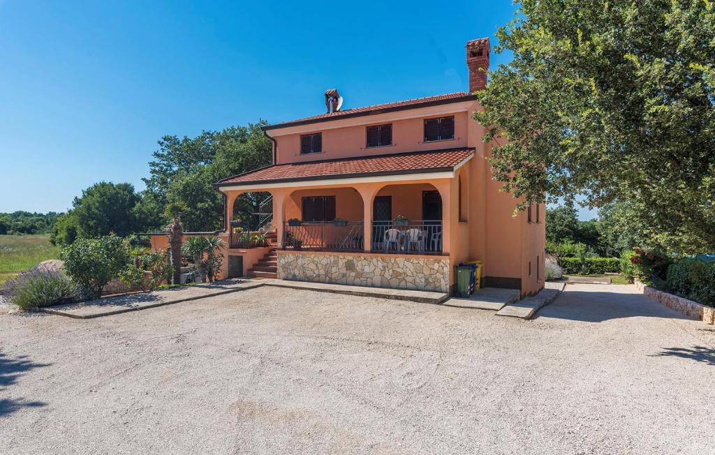 an orange house with a porch and a driveway at Apartment Nino in Kanfanar