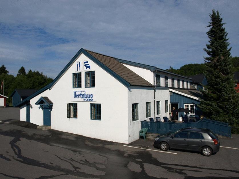 um edifício branco com um carro estacionado em frente em Grimstad Vertshus em Grimstad