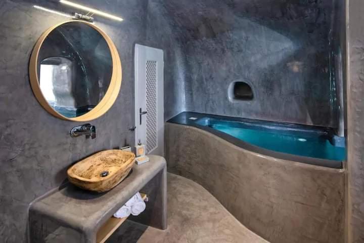 a bathroom with a wooden sink and a tub at Aetheria Villas in Oia