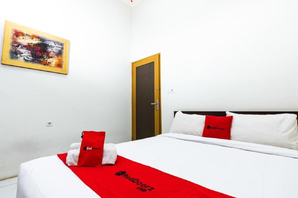 a bedroom with two beds with red and white pillows at RedDoorz @ Hertasning Area 2 in Makassar