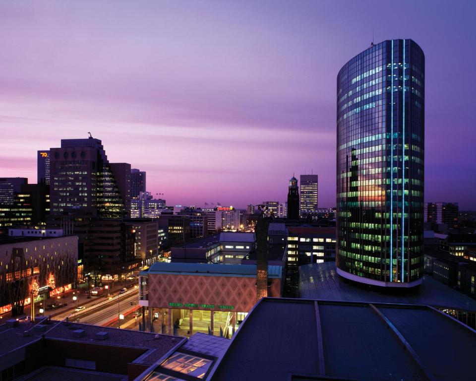 un skyline di notte con un edificio alto di Postillion Hotel WTC Rotterdam a Rotterdam