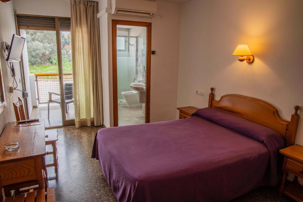 a bedroom with a purple bed and a bathroom at Hotel Herasu in Peñíscola