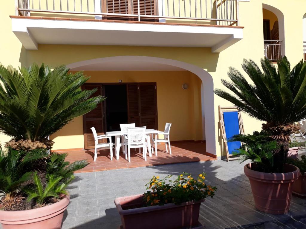 eine Terrasse mit einem Tisch, Stühlen und Pflanzen in der Unterkunft Residence Andrea a mare in Ischia