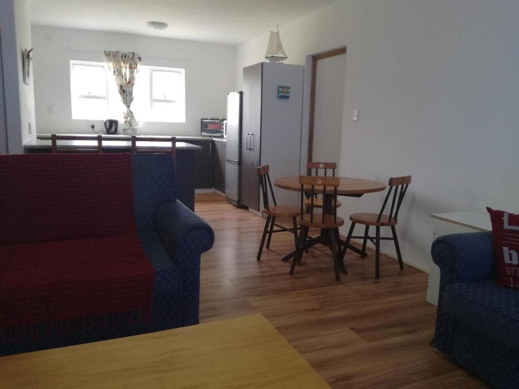 a living room with a table and chairs and a kitchen at Gansbaai Self-Catering Apartment in Gansbaai