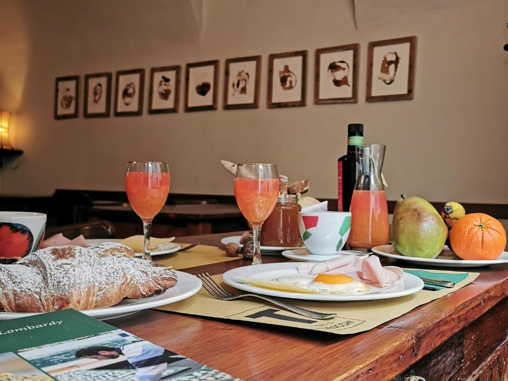 einen Holztisch mit Teller mit Speisen und Weingläsern in der Unterkunft Alla Torre del Barbarossa B&B FORESTERIA in Mandello del Lario