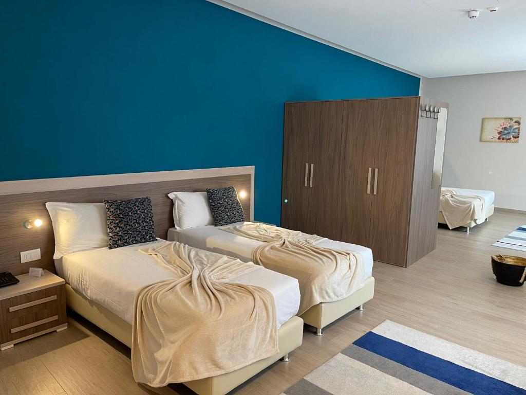 1 dormitorio con 2 camas y pared azul en Palazzo Marignano Hotel, en Melegnano